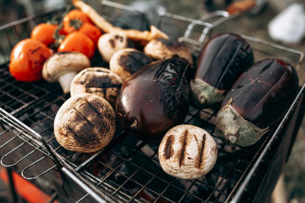 Tomatoes, mushrooms and eggplant grilling on barbecue lattice